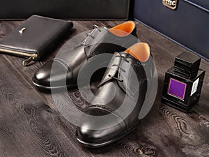 Black leather shoes for the boss on the background of men`s briefcases, card holders and perfume