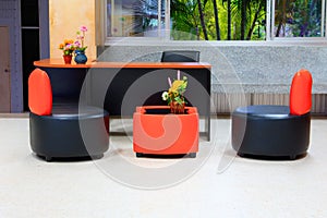 Black leather sofa chair. Orange backrest and wood table internal in office building with copy space add text