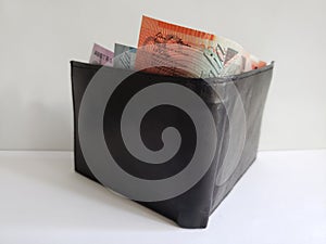 black leather wallet with australian banknotes and white background