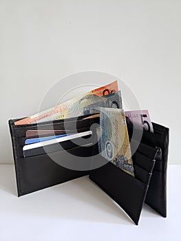 black leather wallet with australian banknotes and white background