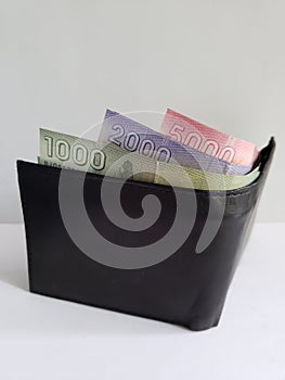 black leather wallet with chilean banknotes and white background