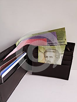 black leather wallet with chilean banknotes and white background