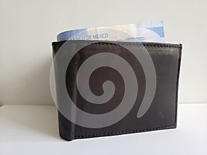 black leather wallet with mexican banknotes and white background