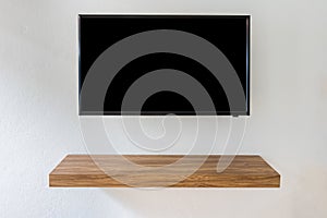 Black LED tv television screen on white wall background with modern wooden table