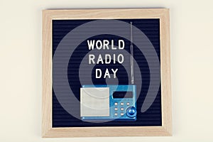 Black letter board with text world radio day with blue radio on white background. Top view. flat lay