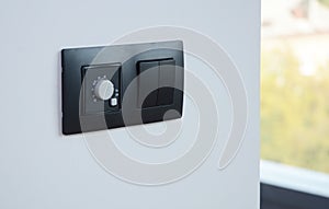 Black light switch on the modern house wall. Socket, air coditioning button,  european power