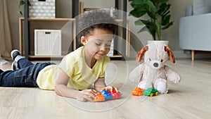 Black little boy play with toy cars with plush teddy