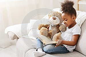 Black little girl reading fairy tale to her teddy bear