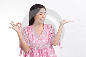 A black long haired Asian cute woman wearing a pink dress is looking at her hand and showing