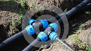 Black long pipe lies and tee adapter in dug-out earth closeup