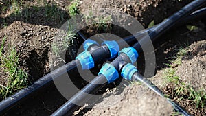 Black long pipe lies and tee adapter in dug-out earth closeup