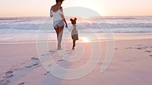 Black lovely mother and daughter walking on beach at sunset