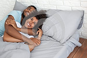 Black loving couple luxuriating in bed together