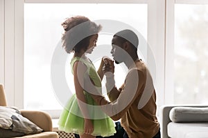 Black loving dad kneel kissing little daughter hand