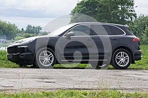 Black luxury car at byroad in autumn time .