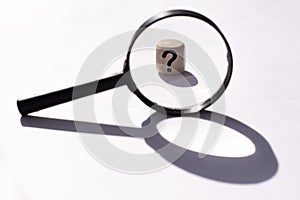 Black Magnifying glass and a question mark on a wooden cube . FAQ frequency asked questions, Answer and Brainstorming