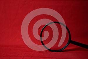 Black Magnifying glass on red table background