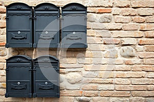 Black mailboxes against brick wall.