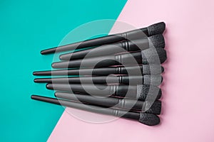 Black makeup brushes on colorful background. Top view of make-up brushes set