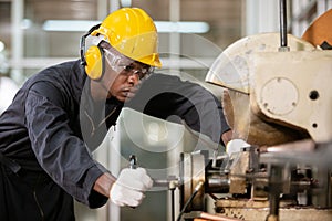 Black male african american workers wear sound proof headphones and yellow helmet working.