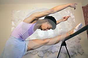 Black male ballet dancer warming up at the barre