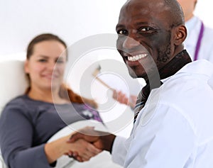 Black male doctor shake hands as hello with female patient