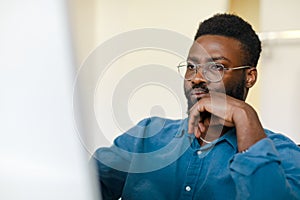 Black male entrepreneur working with computer in office, focused african american businessman looking at monitor screen