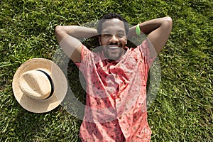 Black male, feeling happy to spend his free time very well laying on the green grass.