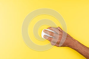 black male hand with white computer wireless mouse on isolated yellow