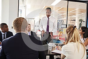 Black male manager stands talking at a business meeting