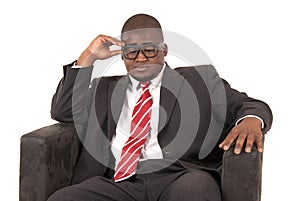 Black male model pondering while sitting is chair wearing a suit