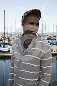 Black male model wearing sweater and newsboy hat at waterfront photo