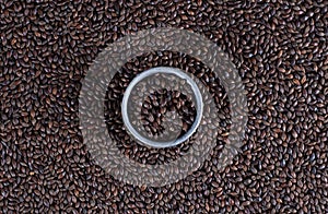 Black malt background with a metal rim in the middle. Malted barley