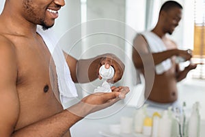 Black Man Applying Shave Foam On Arm In Bathroom, Preparing For Shaving