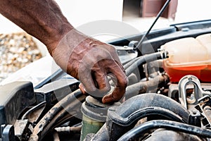 Black man as Auto mechanic working in garage near car engine. Repair service and transport concept. Hands of African American car