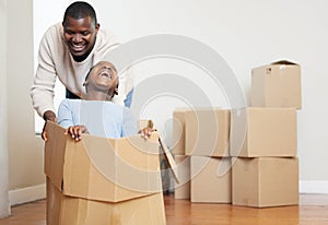 Black man, child and playing with box in new home for moving, relocation or property together. African dad and kid with