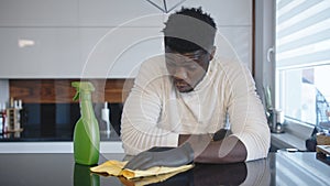 Black man cleaning kitchen. Germaphobe excessively wiping reflective surface