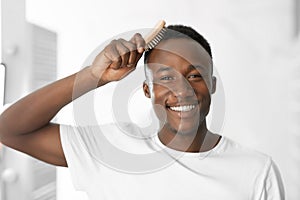 Black Man Combing And Brushing Short Hair In Bathroom Indoors