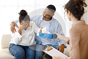 Black man comforting crying wife, couple attend family therapy