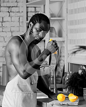 Black man cooking breakfast or lunch on kitchen at home. African American man wearing an apron preparing lemon