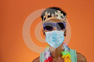 Black man in costume for carnival with pandemic mask isolated on orange background. African man in various poses and expressions