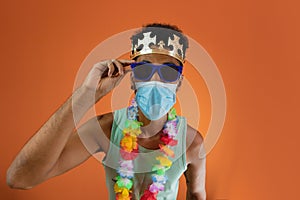 Black man in costume for carnival with pandemic mask isolated on orange background. African man in various poses and expressions