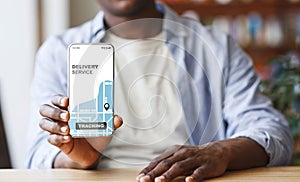 Black Man Demonstrating Smartphone With Opened Delivery Service Tracking App On Screen