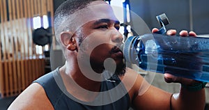 Black man, drinking water and bottle in gym for fitness, health and hydration with lens flare and wellness. Thirsty