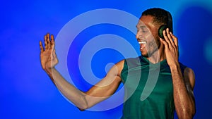 Black Man In Earphones Dancing On Blue Studio Background, Panorama