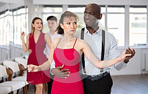 Black man enjoying impassioned merengue with woman in red in studio