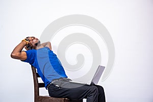 Black man excitedly making a phone call, also carrying a laptop computer on his lap