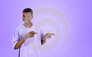 Black man fingers pointing to the side, purple background. Copy space