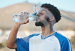 Black man, fitness or soccer player drinking water in training, exercise or workout in football field. Thirsty, sports