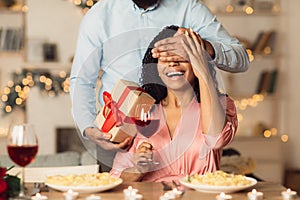 Black man giving box to woman, covering eyes